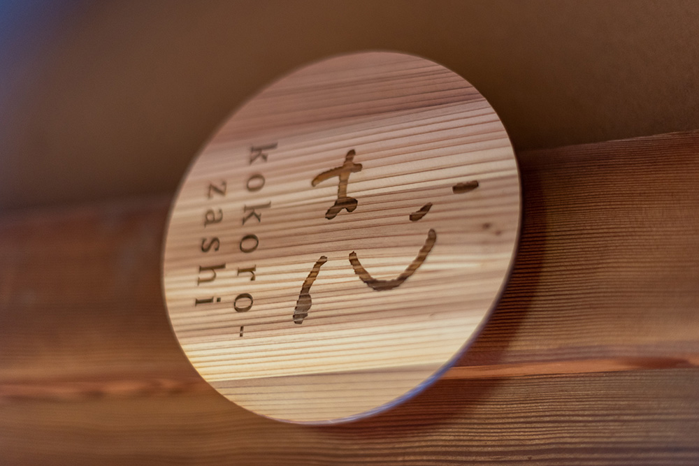 写真：部屋の名前「志 kokorozashi」を焼き付けた円形の木製プレート。