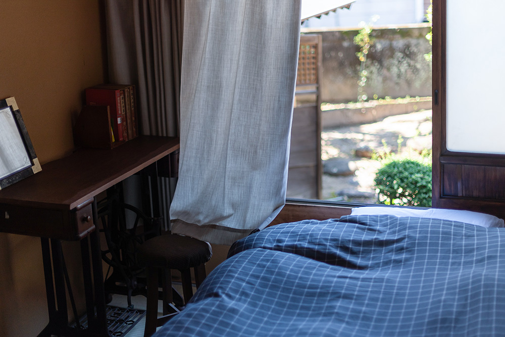 写真：窓際にベッドと机のあるミニマムな和室。