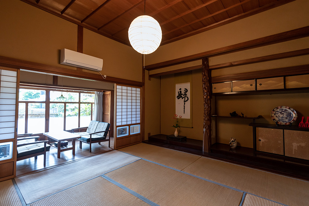 写真：縁側と床の間のある和室。縁側にはテーブルとソファがあり、庭を眺められる。