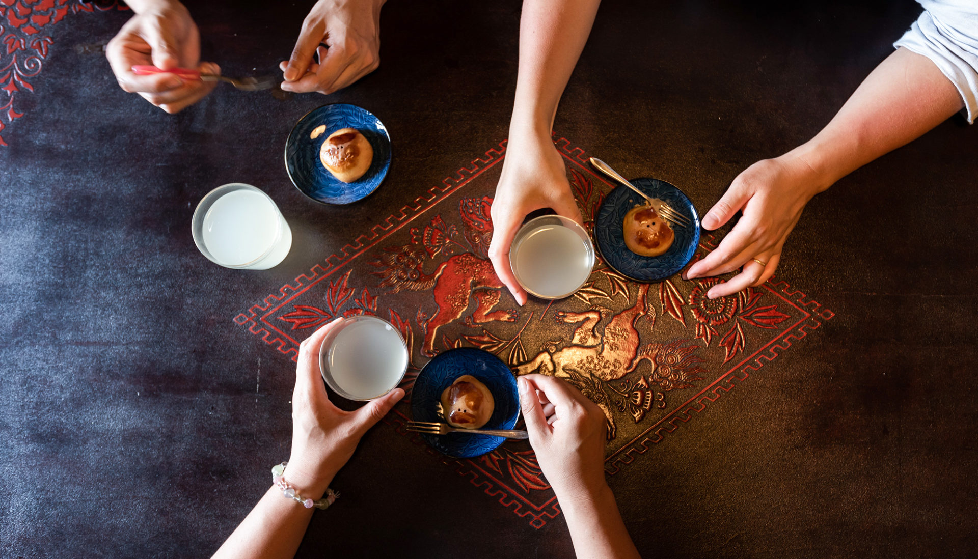 写真：3人がテーブルを囲んでお茶とおやつを楽しんでいるところを真上から見た様子