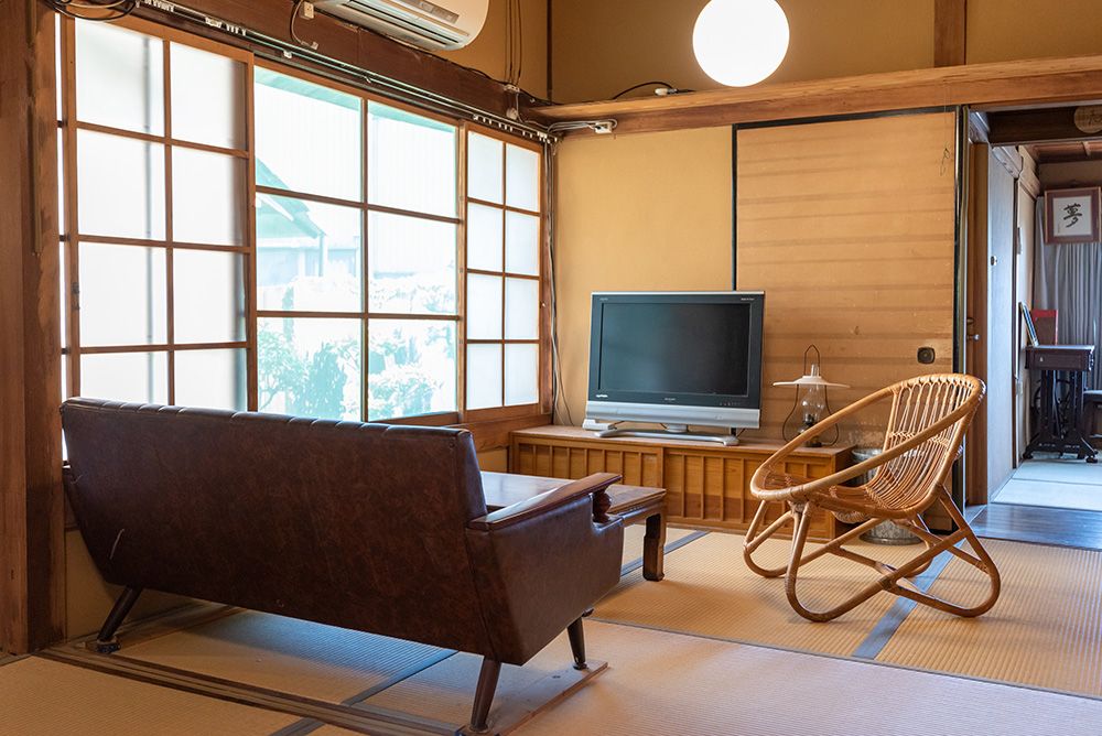 写真：テレビ、ソファ、籐の椅子のある和室