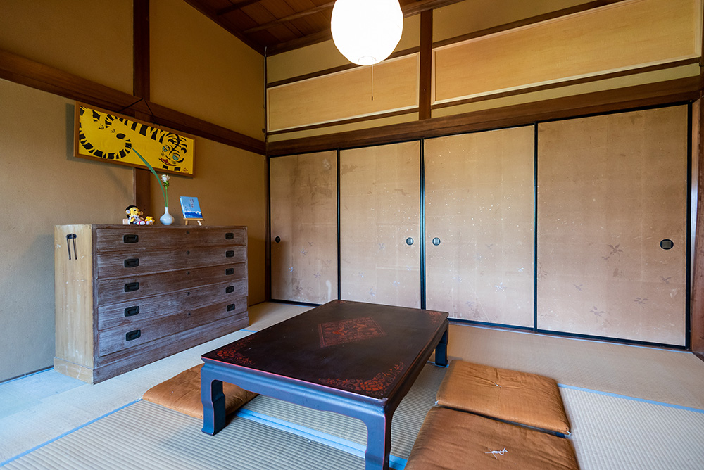写真：真ん中にちゃぶ台が置かれた和室。壁やタンスの上には虎グッズが飾ってある。