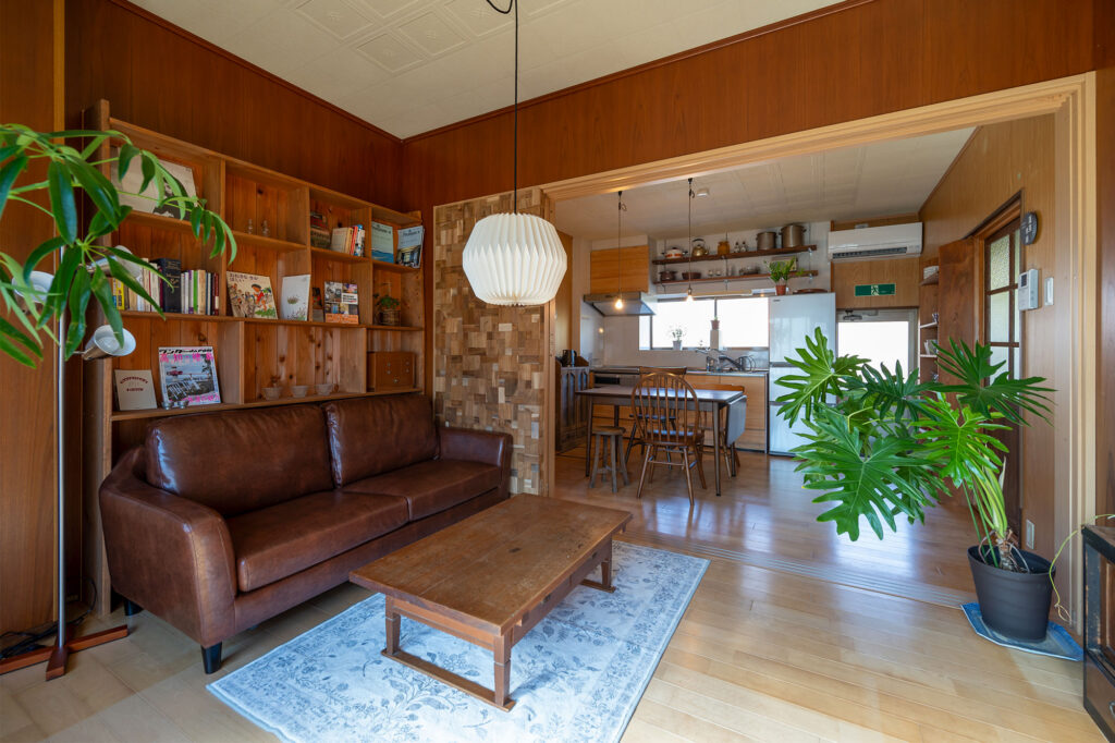 写真:ソファや本棚、観葉植物の置かれた部屋。キッチンとつづき間になっています。