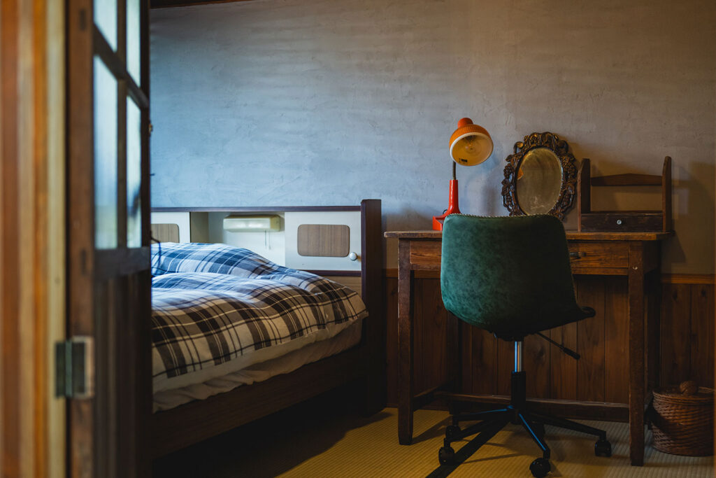 写真:ベッドのそばに机と椅子のある部屋