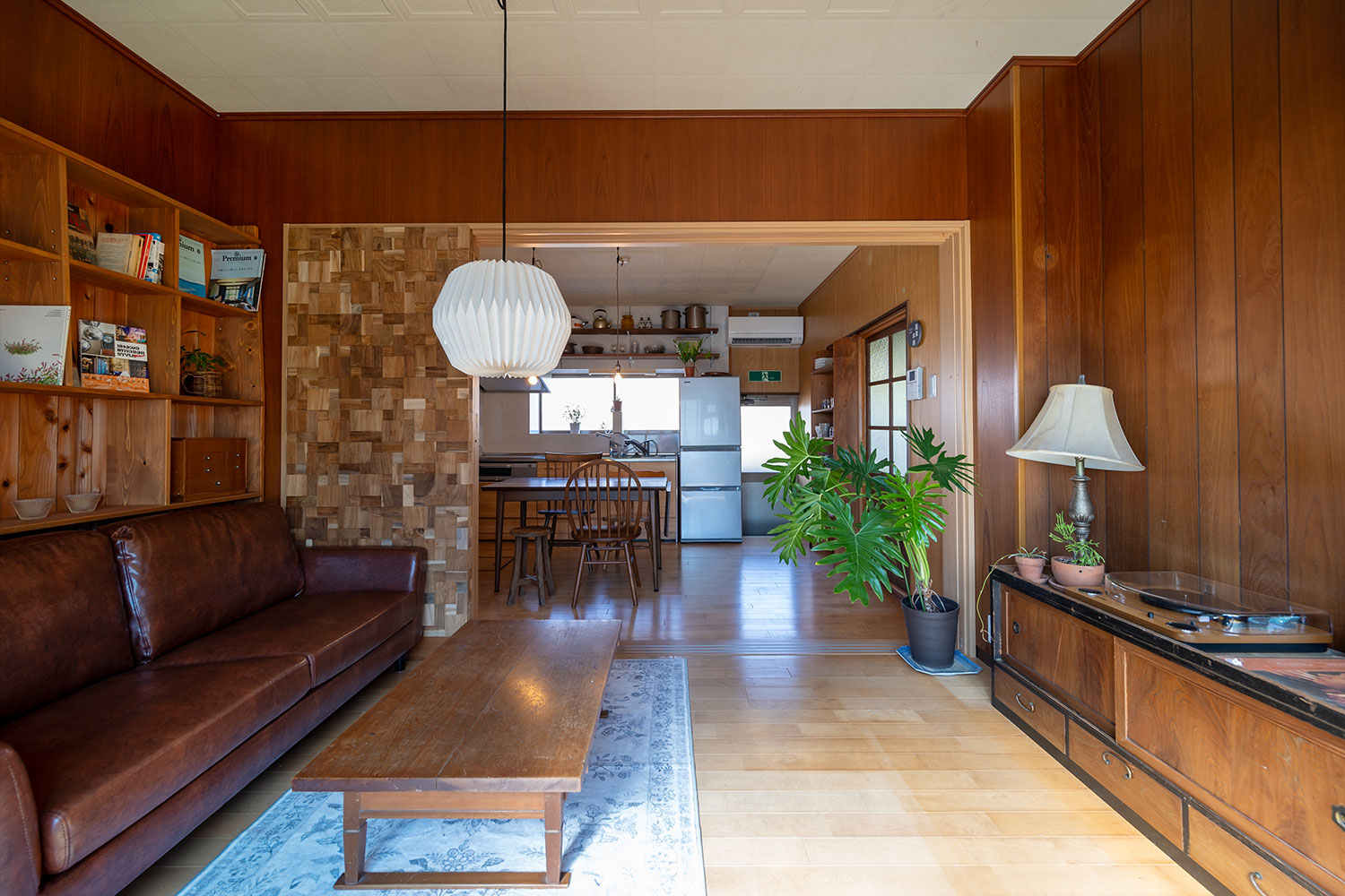 写真:ダイニングとつながったリビング。ソファや本棚があります。