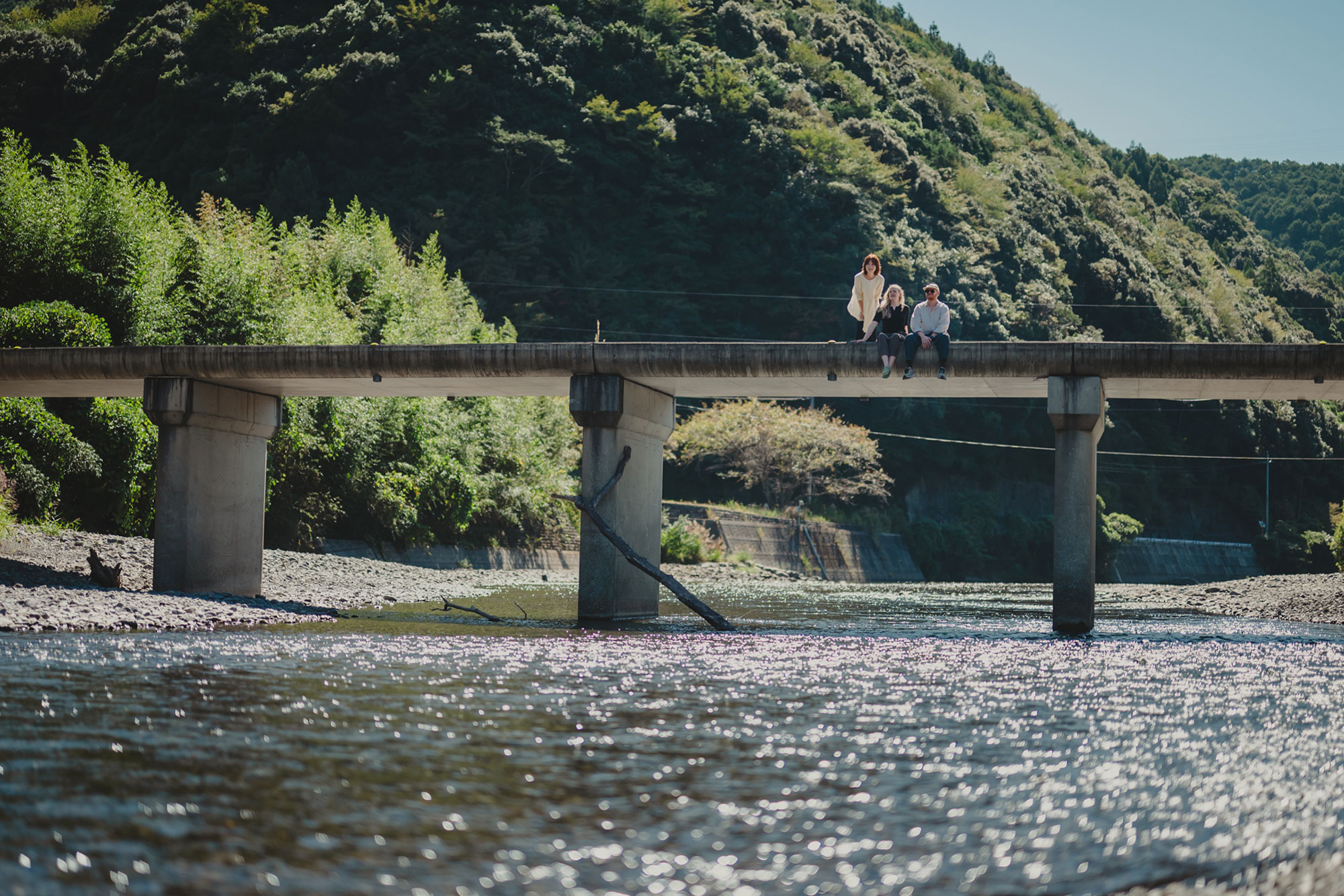 写真:山に囲まれた沈下橋で3人が佇んでいる風景