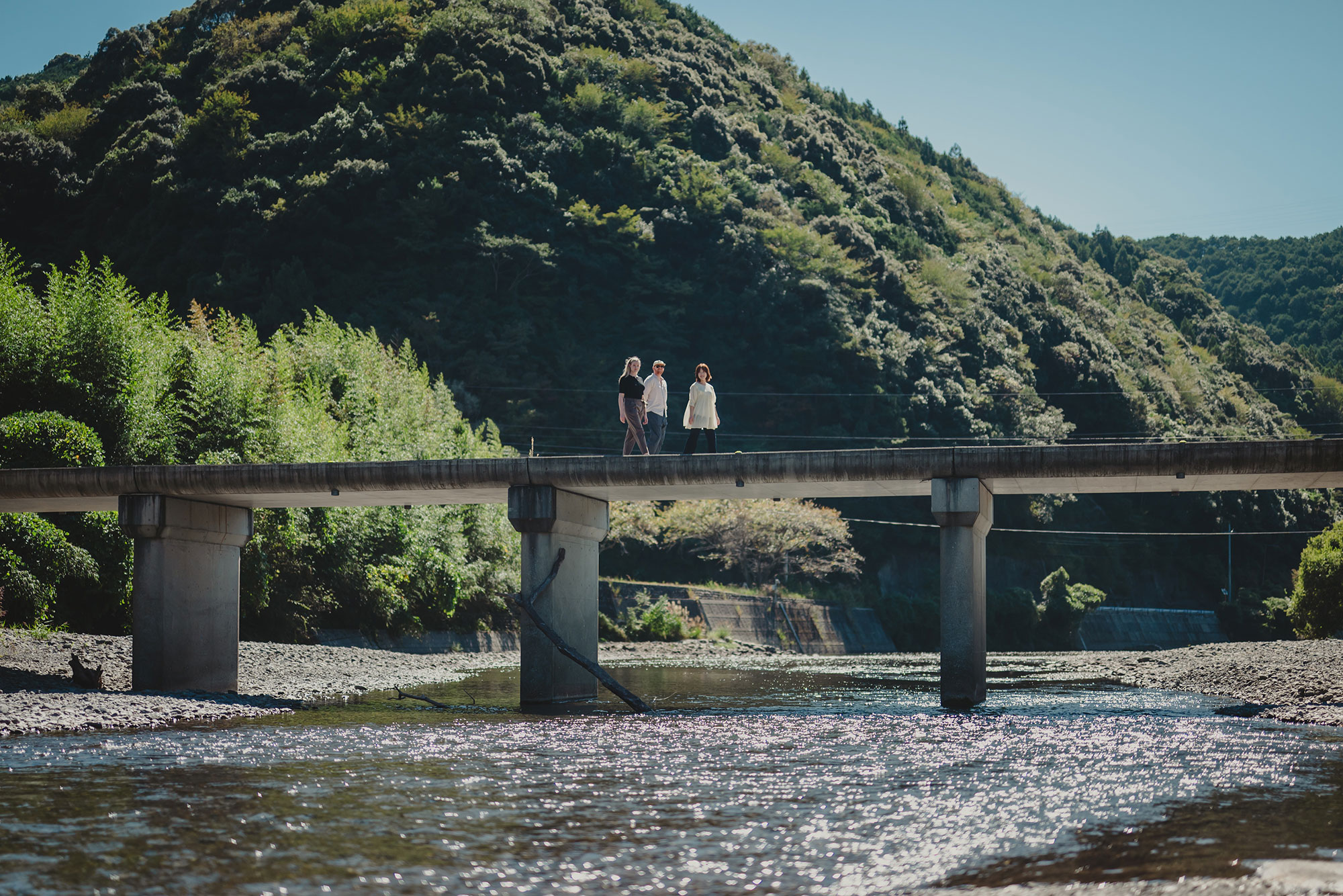 写真:浅い川にかかった沈下橋を歩いて渡る3人