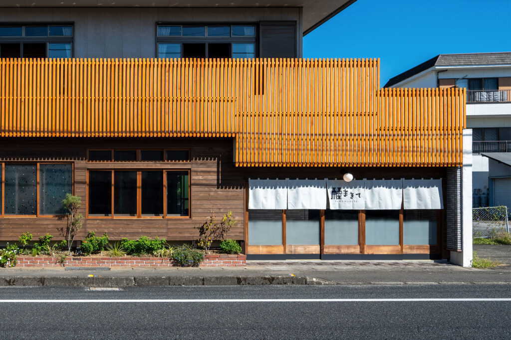 写真:建物の外観。木材を並べたファサードと、白いのれんが目じるしです。