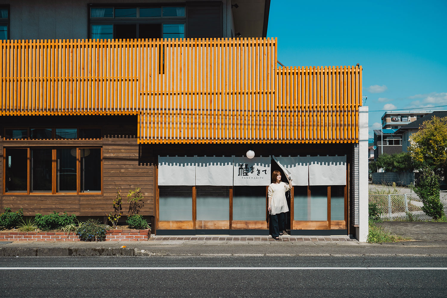 写真:暖簾をくぐって建物から出る女性